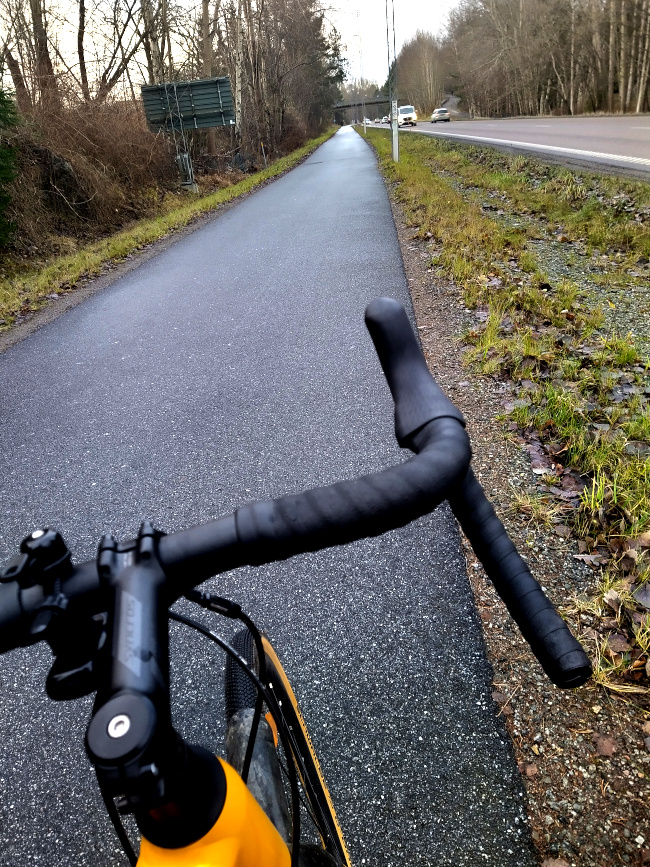 Bild på cykelväg med cykelstyre i förgrunden
