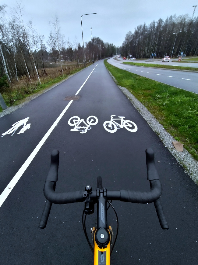 Bild på cykelväg med cykelstyre i förgrunden