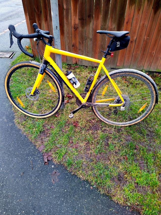 Cykel uppställd mot stolpe vid plank med punktering på bakdäcket
