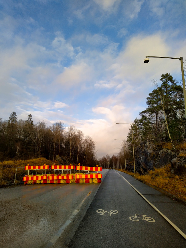 Avstängd bilväg jämte trottar med cykelväg med blå himmel i bakgrunden