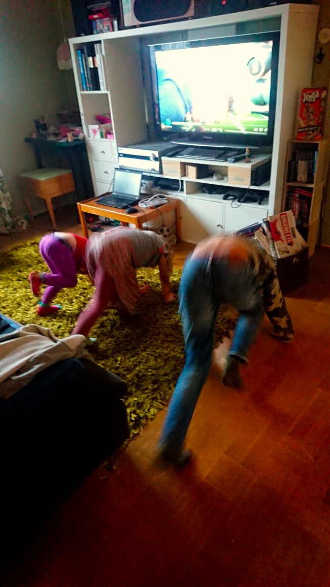 Tre barn gör bergsklättraren framför en TV
